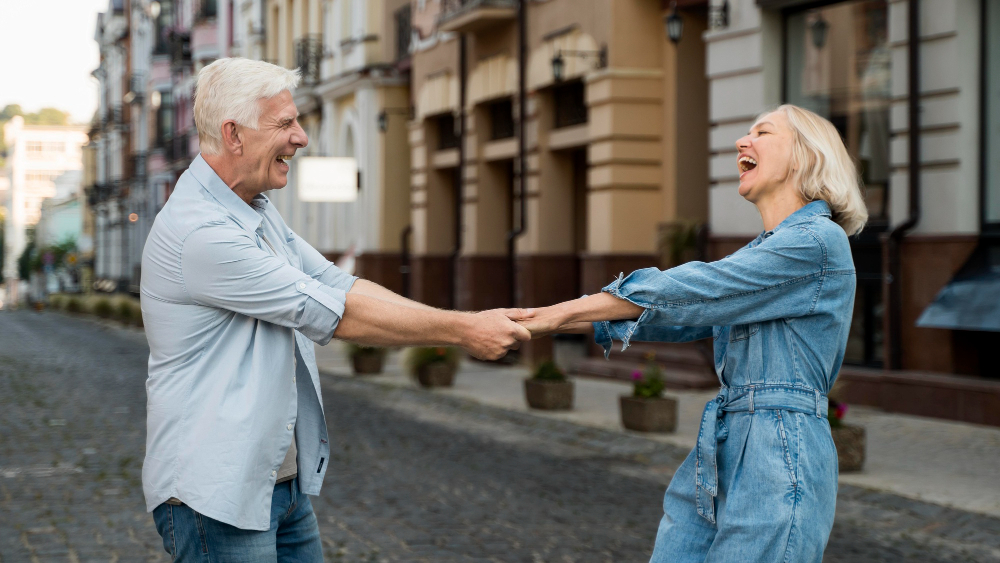 Casal idoso dançando e rindo numa rua